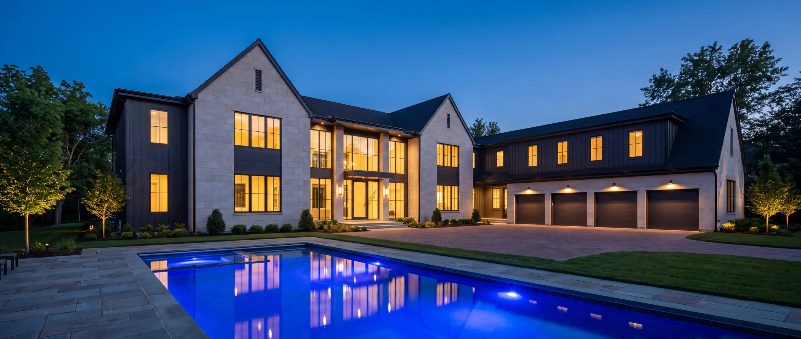 Newly built luxury home at twilight in Bloomfield Hills, Michigan with a blue-lit swimming pool